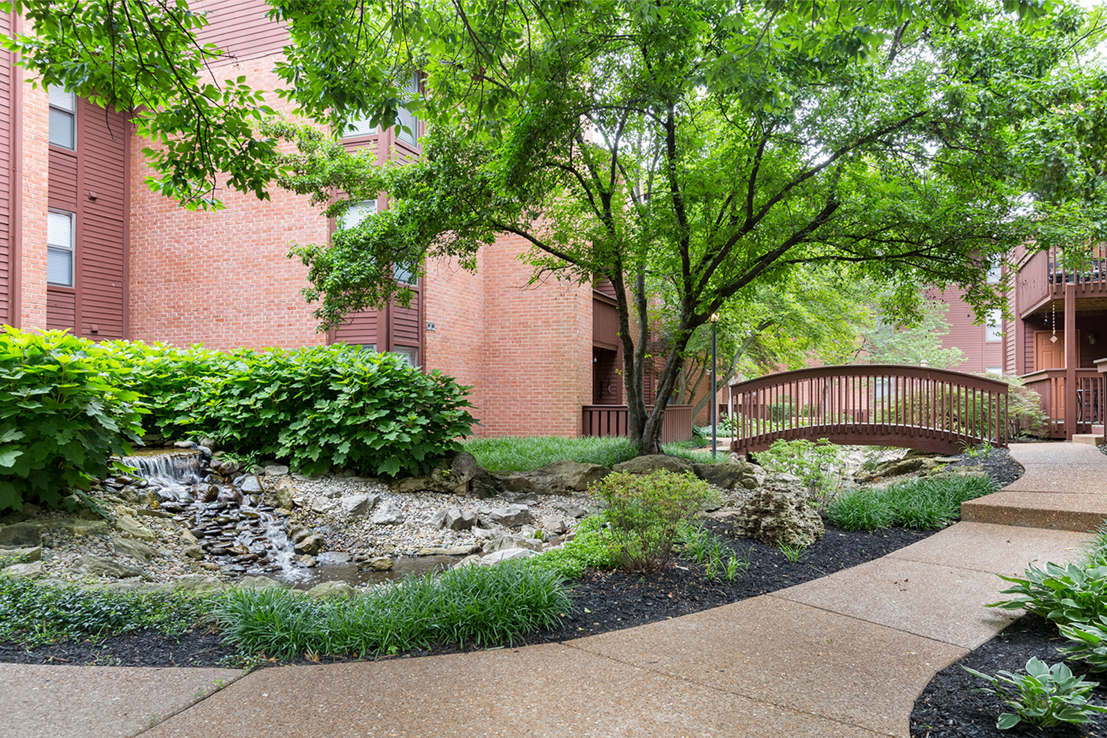A pathway along water with a bridge at Chesterfield Village Apartments